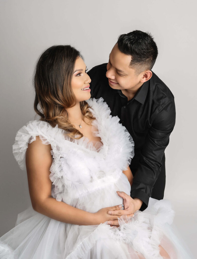 maternity photographer Mississauga area studio, man and woman looking at each other while holding her pregnant belly.