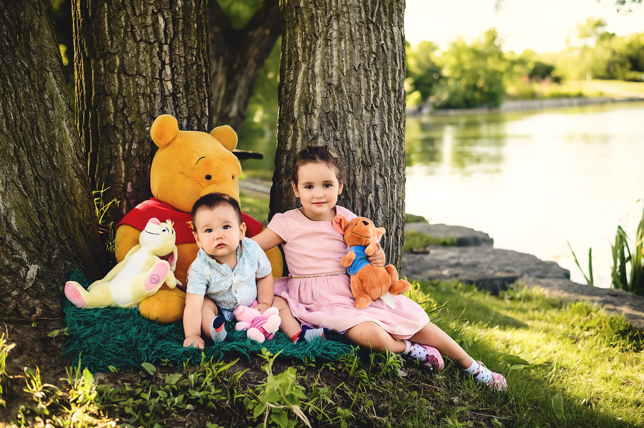 Baby boy sitting with his older sister with Winnie the Pooh stuffed animals at outdoor session by Tamara Danielle Photography in Greater Toronto area.