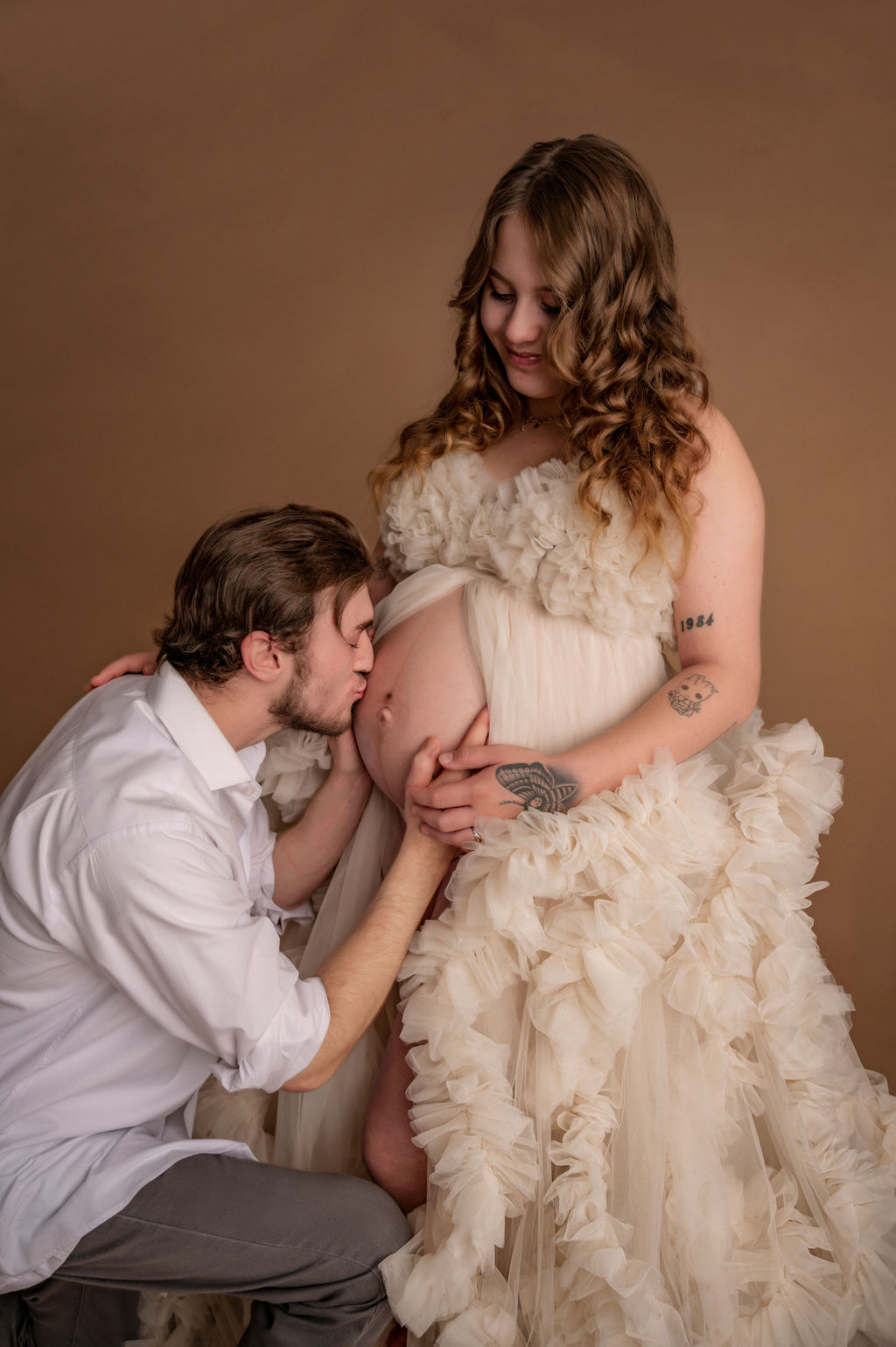 pregnant woman with her husband kissing her belly