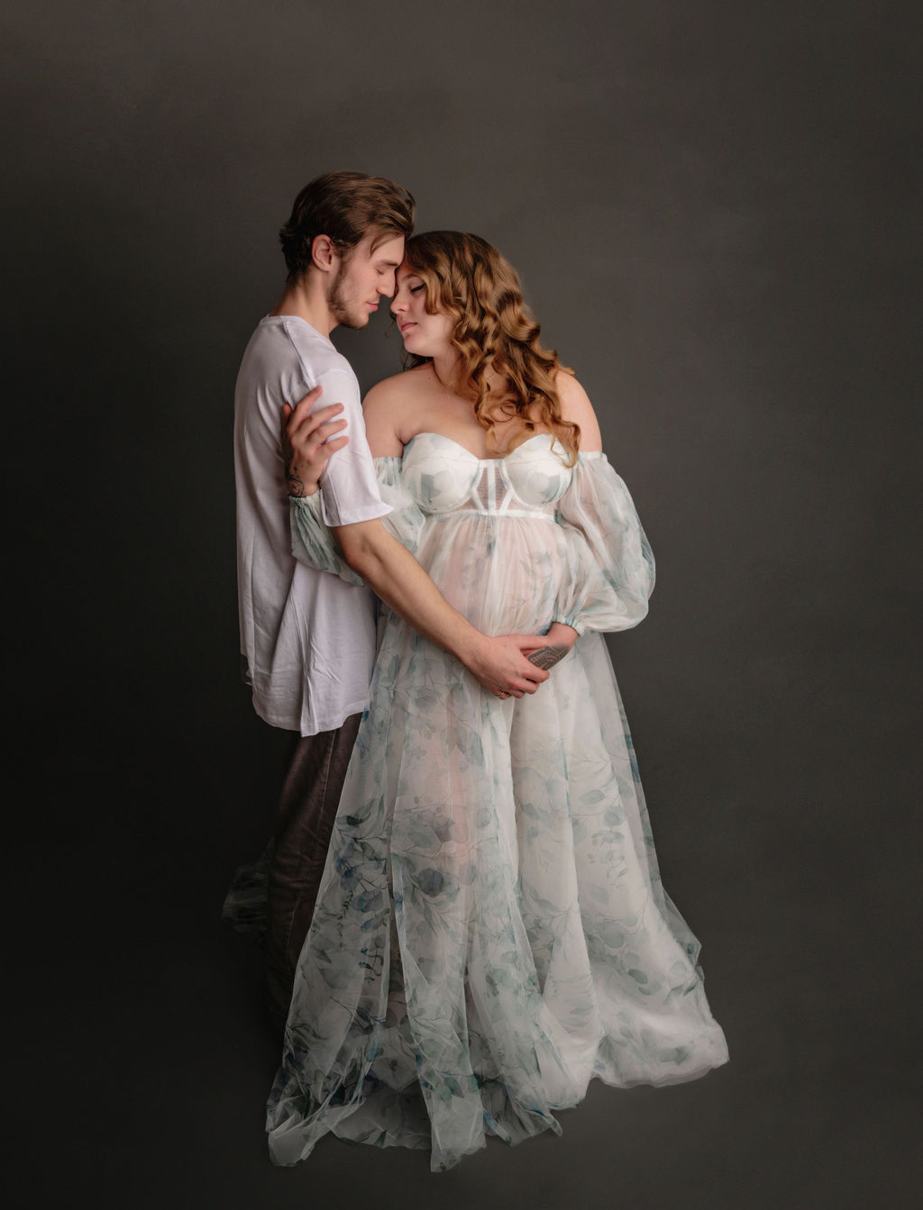 mom to be in sheer maternity gown with her partner holding her bump toronto midwife